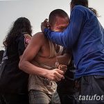 Фото тату: мужчина испытывает боль во время традиционного таиландского ритуала татуировки. Виден процесс нанесения рисунка.