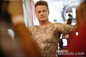 Фотография мужчины с полностью покрытым татуировками телом. Видны детали татуировок в различных стилях.