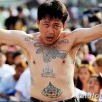 Фотография мужчины с татуировками на груди и руках, выражающего сильные эмоции. Видны изображения тигра и других символов.