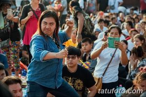 Фотография женщины, выражающей сильные эмоции во время нанесения татуировки. Видно ее напряженное лицо и сосредоточенный взгляд.