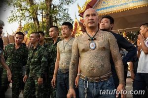 Фотография группы монахов с традиционными татуировками на теле. Видны сложные узоры, покрывающие спины и руки.