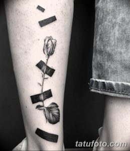 Фото тату: татуировка розы с летящими лепестками, выполненная в стиле blackwork, с использованием плотных черных линий на предплечье.