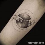 Фото тату: татуировка в стиле dotwork, изображающая руки, тянущиеся друг к другу на фоне круга из точек. Черно-белый рисунок на предплечье.