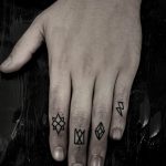 Фото тату: минималистичные руны на фалангах пальцев. Тонкие черные линии, геометрические символы, современный стиль татуировки.