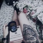 Фото тату на ноге девушки, читающей книгу. Рисунок татуировки изображает лицо ангела в стиле реализм с элементами готики и цветочным орнаментом.
