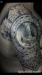 Фото тату: реалистичное изображение молота Тора на руке. Детализированный рисунок с использованием черного и серого цветов.