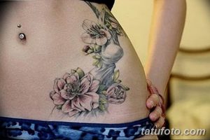 Фото татуировки ветки цветущей сакуры на боку женщины. Нежные розовые цветы и детально проработанные листья создают изящный и женственный образ.