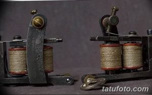 Фотография двух старинных тату-машинок, выполненных в винтажном стиле. Металлические корпуса с катушками и пружинами.