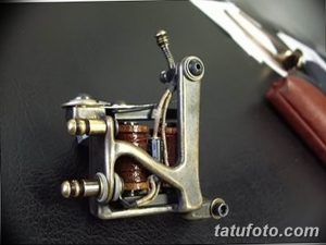 Фотография внутреннего устройства тату-машинки, демонстрирующая катушки, пружины и другие детали.