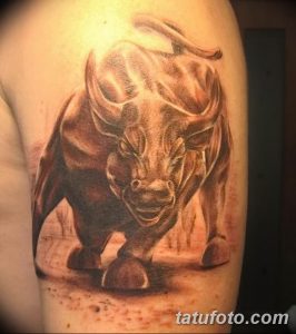 Фото тату быка на плече в реалистичном стиле. Детализированное изображение головы быка с мощными рогами и свирепым взглядом.