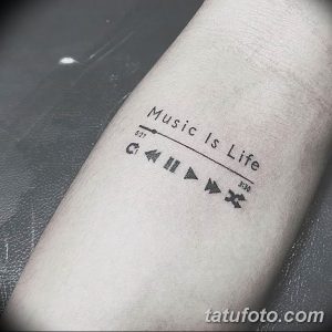 Фото тату на предплечье с изображением плеера, временной шкалы и надписи 'Music Is Life'. Черно-серый рисунок татуировки в минималистичном стиле.