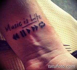 Фото тату на предплечье с изображением плеера и надписью 'Music is Life'. Черный рисунок татуировки в минималистичном стиле.