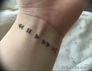 Фото тату на запястье с изображением минималистичных символов управления медиа: перемотка назад, пауза, воспроизведение, стоп.