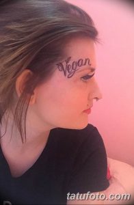 Фото тату надписи 'Vegan' на лбу девушки. Изображение демонстрирует смелый выбор и отражает жизненные принципы.
