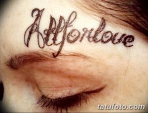 Фото тату надбровной дугой: надпись 'All for love' выполненная тонким шрифтом. Черно-белое изображение, демонстрирующее необычное расположение татуировки.