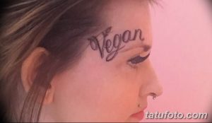 Фото татуировки на лице девушки с надписью 'Vegan' и изображением листа. Яркий и выразительный рисунок.