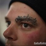 Фото мужчины с татуировкой на лбу. Над бровью видна надпись, выполненная черным цветом.