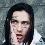 Фото девушки с длинными черными волосами и татуировками на лице. На щеках и под глазом видны надписи 'HATE' и 'MOMME'.