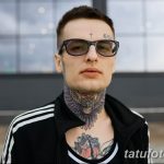 Фото мужчины в очках с татуировками на лбу, шее и груди. На лбу видна маленькая татуировка креста, на шее – изображение совы.