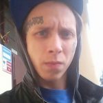 Фото татуировки на лице мужчины: надпись и узор расположены на лбу. Тату выполнено в черном цвете.