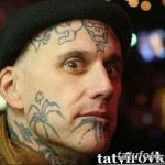 Фото татуировки на лице мужчины: различные рисунки, включая звезды, паука и абстрактные узоры, расположены на щеках, лбу и подбородке.