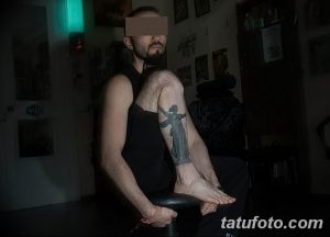 Фото тату Богини Победы с мечом на руке. Рисунок татуировки в стиле реализм, выполненный в серых тонах. Подходит для тех, кто ценит силу и красоту.