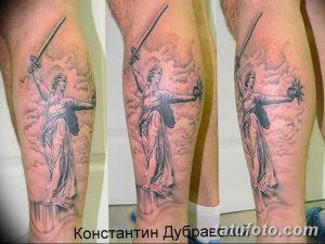 Фото тату Родина-мать на ноге, выполненное в черно-серых тонах. Детализированный рисунок татуировки с акцентом на светотень.