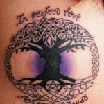 Фото тату на ключице: Древо жизни с кельтским узором и надписью 'In perfect love and perfect trust'. Красочный рисунок татуировки.