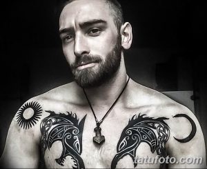 Фото тату: изображение двух волков, обрамленных лунным серпом, на груди. Детализированная проработка шерсти и глаз.