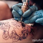Фото процесса нанесения татуировки: мастер в голубых перчатках работает тату-машинкой над эскизом на коже клиента. Виден контур рисунка.