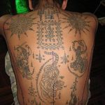 Фото тату на спине: традиционная тайская татуировка с изображением тигра, священных символов и геометрических узоров, выполненная в черных чернилах.