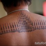 Фотография масштабной татуировки на спине мужчины, выполненной в традиционной тайской технике сакральных линий. Татуировка состоит из множества вертикальных линий, геометрических фигур и символов.
