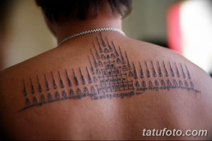 Фотография масштабной татуировки на спине мужчины, выполненной в традиционной тайской технике сакральных линий. Татуировка состоит из множества вертикальных линий, геометрических фигур и символов.