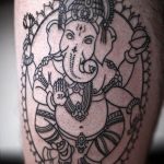 Фото тату Ганеши на руке, выполненное в технике blackwork. Детализированный рисунок татуировки с множеством мелких элементов и узоров.