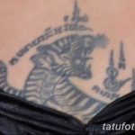Фото тайской татуировки с изображением головы мифического существа, возможно, дракона или наги. Черные линии и традиционные узоры создают загадочный и мощный образ.