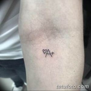 Фото тату на запястье: минималистичное изображение группы крови 'A+' с сердечком вместо буквы 'O'. Татуировка выполнена в черном цвете.