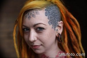 Фото тату: сложный кельтский узор на голове девушки с дредами. Татуировка выполнена в черном цвете и покрывает часть лба и виска.