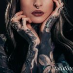 Фотография девушки с множеством татуировок на руках и шее. Татуировки включают в себя цветы, бабочек, надписи и абстрактные узоры, выполненные в черных и серых тонах.