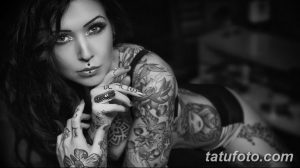 Фотография девушки с длинными темными волосами и множеством татуировок на руках и груди, выполненных в черно-белой гамме.