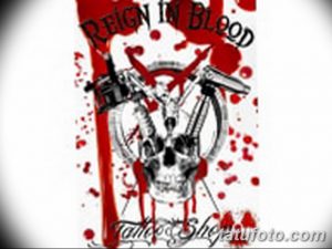 Фото татуировки черепа с надписью "Reign in Blood" и брызгами крови на спине. Графичный рисунок татуировки в черном и красном цветах.