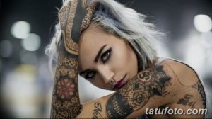 Фотография девушки с короткими светлыми волосами и татуировками на руках, демонстрирующая сочетание геометрических узоров и цветочных мотивов.