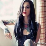 Фотография девушки с длинными темными волосами и множеством татуировок на руках и шее, демонстрирующая разнообразие рисунков татуировок.
