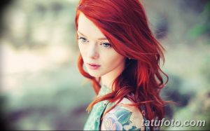 Фотография девушки с рыжими волосами и татуировкой на плече, демонстрирующая нежность и красоту татуировки.