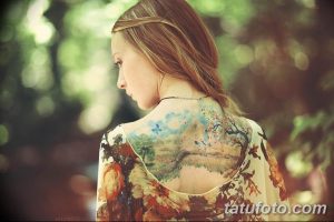 Фото тату на спине: реалистичный пейзаж с лесом, деревьями, небом и птицами, выполненный в черно-серых тонах.