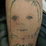 Фото тату на руке с изображением лица ребенка и надписью. Простой черно-серый рисунок.