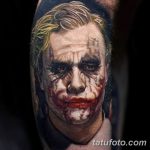 Фотография реалистичной татуировки на предплечье с изображением Джокера, персонажа фильма, с характерным гримом и безумной улыбкой.