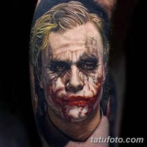 Фотография реалистичной татуировки на предплечье с изображением Джокера, персонажа фильма, с характерным гримом и безумной улыбкой.