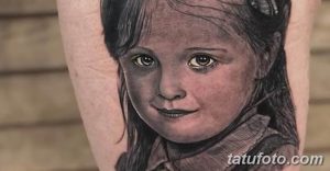 Фото тату: реалистичный портрет маленькой девочки с лучистыми глазами и милой улыбкой, выполненный на предплечье.