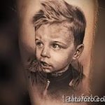 Фотография татуировки с реалистичным портретом маленького мальчика, выполненной в черно-серых тонах на руке.