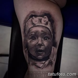 Фото тату реалистичного портрета маленькой девочки с бантиком на руке. Детализированный рисунок в черно-белых тонах.